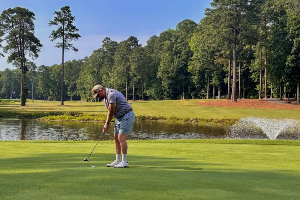 The Brandermill golf course green photographed from above, bordered by pines and water