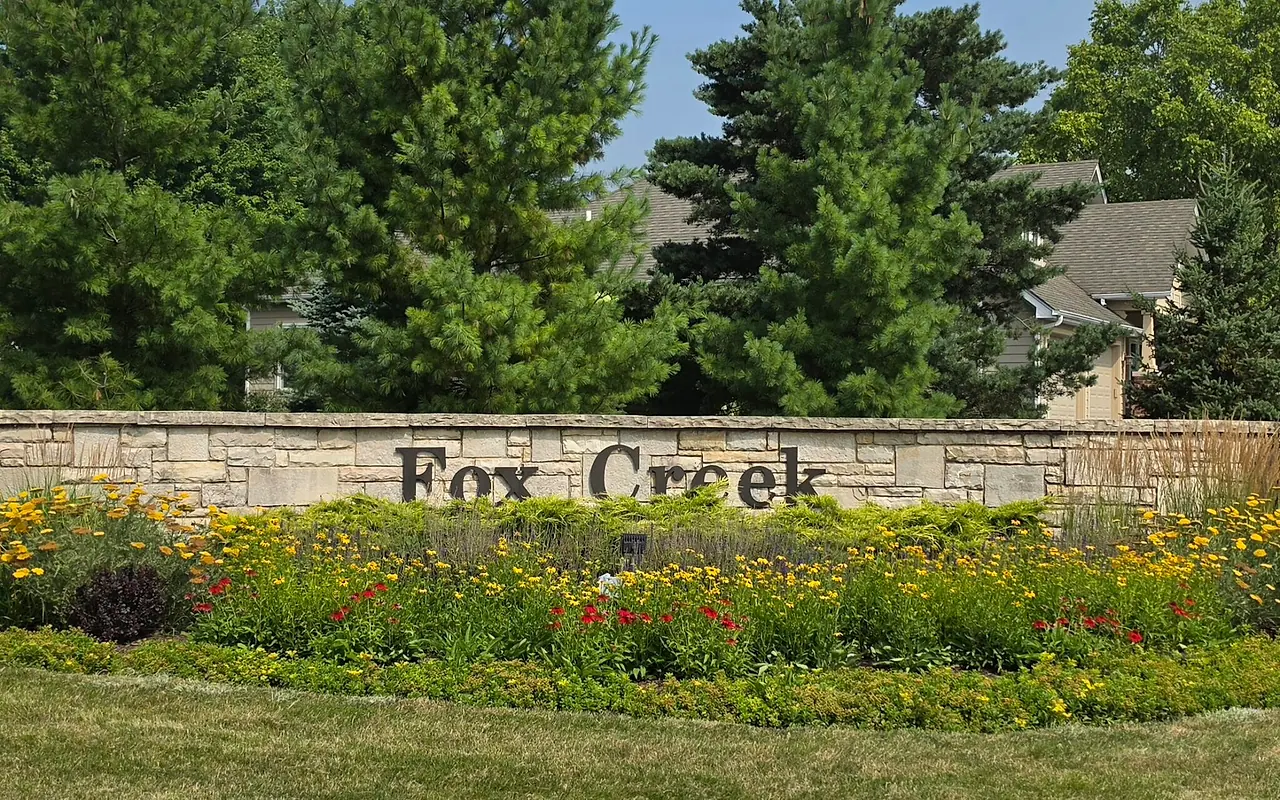 The landscaped Fox Creek entrance monument with homes and trees behind it