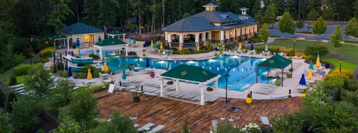 The Hallsley pool and pavilions photographed from the air at dusk, lights on across the deck