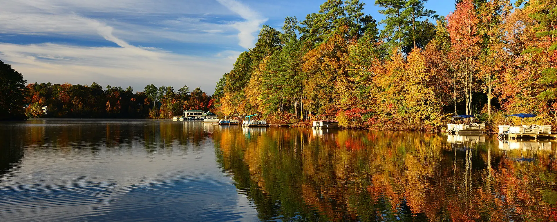 Woodlake shoreline, boats, and autumn trees reflected in Swift Creek Reservoir