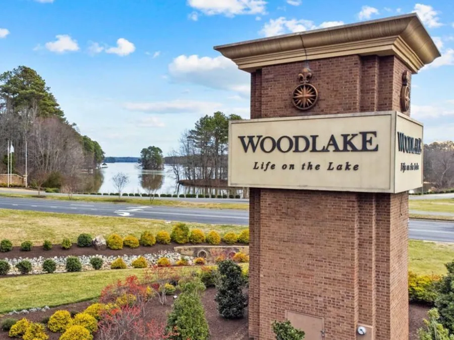 The brick Woodlake entrance monument reading Life on the Lake, with Swift Creek Reservoir behind it